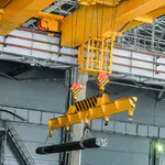 Brückenkran in einer Stahlhalle beim Heben von Stahlbündeln – gesteuert durch esco-Frequenzumrichter mit präziser Hubwerksregelung und Sicherheitsfunktionen.