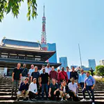 Das Foto zeigt ein Gruppenbild vor dem Zojoji-Tempel mit Tokyo Tower im Hintergrund