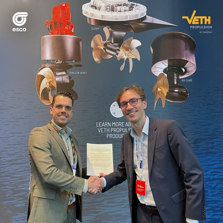 Managing Director Bastiaan van Zuijlekom und Laurent Schmidt, CEO der ESCO Group, besiegeln ihre Partnerschaft per Handschlag auf der Europort 2025 vor einer Präsentation maritimer Antriebssysteme von Veth Propulsion.