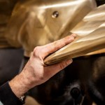 Nahaufnahme eines Bronzepropellers für Veth Ice Class Thruster mit Handprüfung der Propellerkante für präzise Verarbeitung und Qualität.